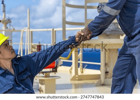 Teamwork concept at sea featuring two ship officers, one helping the other rise from the deck.