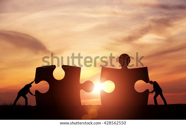 Teamwork concept. Two businessman\
connecting jigsaw puzzle pieces together with copy\
space