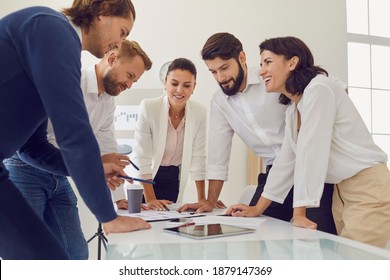 Teamwork, cooperation, startup, brainstorm concept. Group of young smiling office workers business people standing around table in office and having brainstorm about new project or startup together