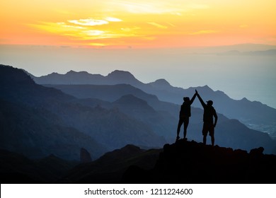 Teamwork Ehepaar hilft Hand Trust Hilfe, Silhouette Erfolg in den Bergen. Team der Kletterer Mann und Frau. Wanderer feiern mit Händen hoch, helfen einander auf der Bergkulisse, Sonnenuntergang.