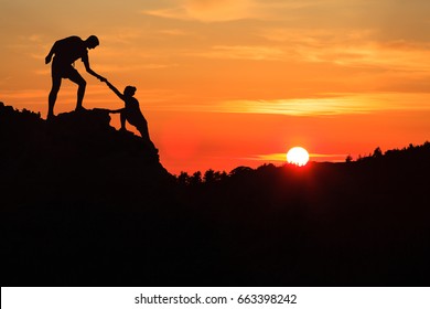 Teamwork couple helping hand trust silhouette in inspiring mountains. Team of climbers assistance man and woman hiker, help each other on top of mountain, beautiful sunset landscape in Corsica France - Powered by Shutterstock