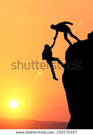 Teamwork couple hiking help each other trust assistance silhouette in mountains, sunset. Teamwork of two men hiker helping each other on top of mountain climbing team, beautiful sunset landscape.