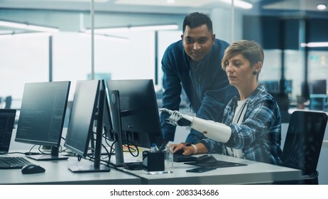 Teamwork In Diverse Inclusive Office: Project Manager Talks with Woman with Disability with Prosthetic Arm Work on Desktop Computer. Professionals Software Engineers Create e-Commerce App Solution