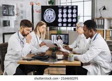 Teamwork Of Diverse Neuroscientists Sharing Lists With Researchings While Discussing Disease Problems In Science Laboratory. Healthcare Workers Using Monitor With X Ray Scan Showing Brain Anomalies.