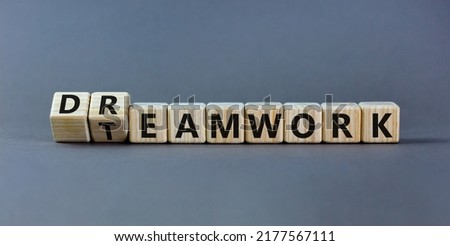 Teamwork and dream work symbol. Turned wooden cubes and changed the word 'dreamwork' to 'teamwork'. Beautiful grey table, grey background. Business, teamwork and dream work concept, copy space.