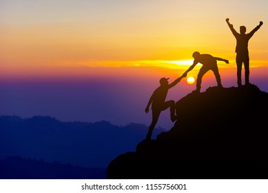 Teamwork friendship  hiking help each other trust assistance silhouette in mountains, sunrise. Teamwork of two men hiker helping each other on top of mountain climbing team beautiful sunrise landscape