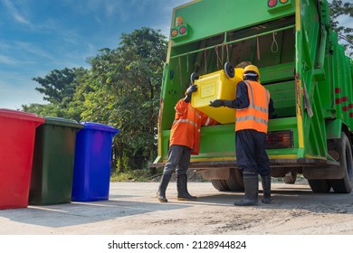 Teamwork garbage men working together on emptying dustbins for trash removal with truck loading=