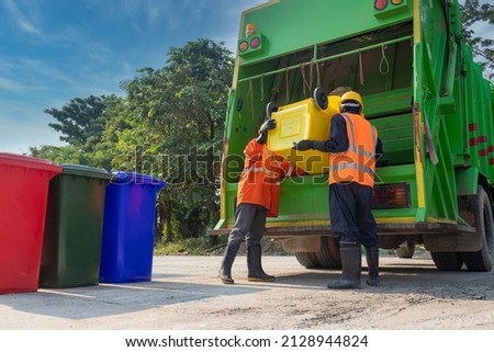 Teamwork garbage men working together on emptying dustbins for trash removal with truck loading waste and trash bin. Garbage collector.