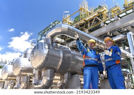 teamwork: group of industrial workers in a refinery - oil processing equipment and machinery 