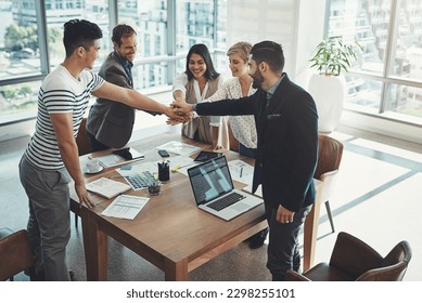 Teamwork means providing support to each other. a diverse group of businesspeople joining their hands in a huddle in an office.