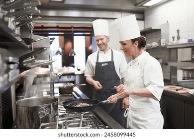 Teamwork, meat and chef with frying pan in kitchen for catering service, fine dining or prepare dish. Hospitality, presentation and people for cooking meal, food industry or dinner in restaurant - Powered by Shutterstock