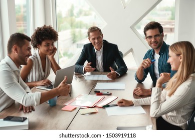 Teamwork. Multicultural team discussing something and smiling while sitting at the office table - Shutterstock ID 1503919118