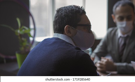 Teamwork In Office During Pandemic, Office Workers At Business Meeting Respecting Social Distance, Rear View Of Businessman Wearing Protective Mask Sitting At Negotiating Table With His Colleagues