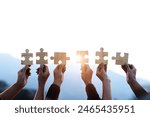 Teamwork and partnership concept. Hands are raised against a bright, white sky, each holding a piece of a wooden jigsaw puzzle. teamwork, problem-solving, Charity, volunteer. Unity, team business.