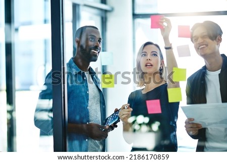 Teamwork, planning and reading sticky notes while brainstorming, talking or sharing ideas. Diverse group of creative businesspeople meeting, training with tablet or paperwork to innovate vision plan
