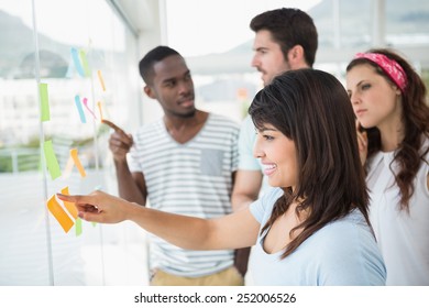 Teamwork pointing and reading sticky notes in the office