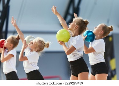 Teamwork at sports. Group of kids, little girls, beginner gymnastics athletes in sports uniform at training at sports gym, indoors. Concept of beauty, sport, achievements, studying, goals, skills - Powered by Shutterstock