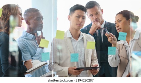 Teamwork, strategy and collaboration with planning business people writing sticky notes on a board or window. Serious thinking and creative problem solving with diverse group on a innovation mission - Shutterstock ID 2194220287