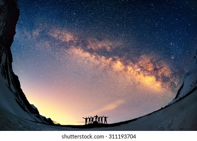 Teamwork and support. A group of people are standing together holding hands against the Milky Way in the mountains.  - Shutterstock ID 311193704