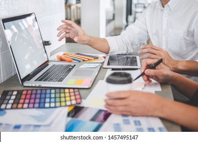 Teamwork of young creative designers working on project together and choose color swatch samples for selection coloring on digital graphic tablet and equipment at workplace.