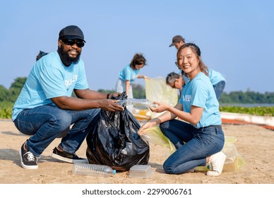 teamwork young diverse friends happy to clean up river beach together, group of volunteers charitable working picking trash into garbage bags separating reused plastic for recycling waste management - Powered by Shutterstock