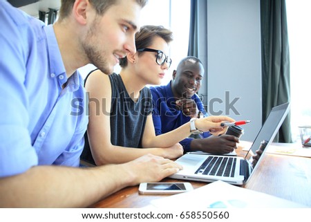 Teamwork,brainstorming concept.Young creative managers team working with new startup project in modern office. Contemporary notebook on wood table.