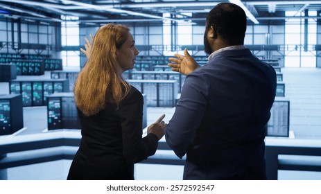 Teamworking admin colleagues inspecting server room hardware. IT expert and colleague supervising data center establishment, checking equipment, monitoring performance, camera A