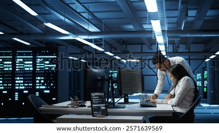 Teamworking colleagues in high tech data center managing and maintaining databases, ensuring data integrity, security and availability. Team of specialists updating server room systems, camera B