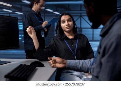 Teamworking programmers in data center using diagnostic tools and system monitoring software to identify root cause of errors. Multiethnic team in server farm repairing equipment together