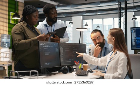 Teamworking programmers developing software applications, working together to optimize code. Tech startup team doing brainstorming in office, using AI to solve bottlenecks, camera A