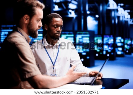 Teamworking repairmen dealing with server hub system failures, using laptop to order data center racks with high availability features to minimize downtime and prevent crashes