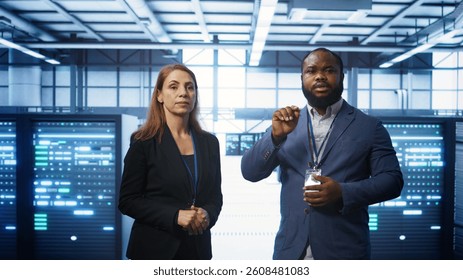 Teamworking technicians in high tech data center workspace looking at hologram visualization. Programmer and colleague working on securing server room hardware using AR tech, camera B