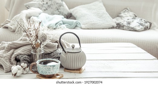 A Teapot And A Beautiful Ceramic Cup With Decor Details In A Hygge Style Living Room. The Concept Of Home Comfort And Modern Style.