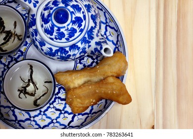 Teapot blue flowers. Food placed inside deep-fried doughstick. Smoke from a hot cup of tea.