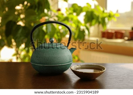 Teapot and cup of freshly brewed tea on wooden table indoors. Traditional ceremony