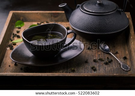 Teapot and cup with green tea on a wooden background