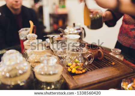 Teapot and cup of tea on woodensurface with blurry nature background.