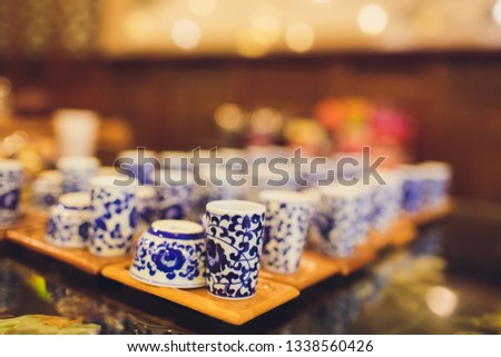 Teapot and cup of tea on woodensurface with blurry nature background.