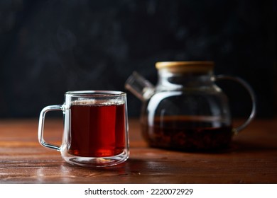Teapot and cup of tea standing on a brown table