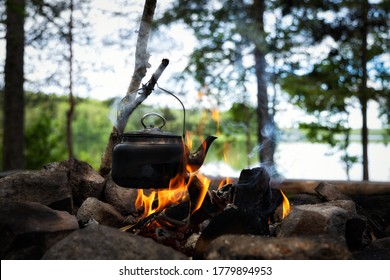 Teapot over the fire. Old vintage kettle. Beautiful campfire in a tourist camp in the summer forest. Survival in the forest. 
