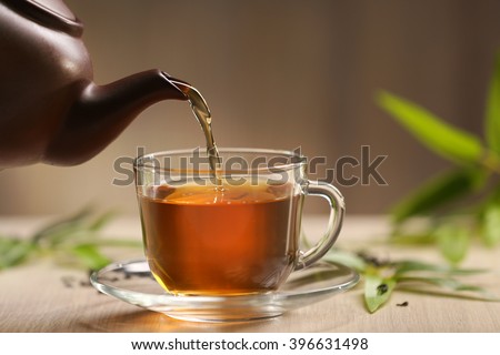 Teapot pouring tea in cup