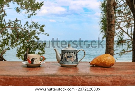 Teapot, tea cup on a wooden table, tea ceremony on the shore of a beautiful bay with azure water. The concept of relaxation, rest.