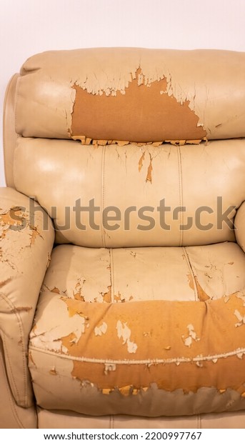 Tear damaged old synthetic leather brown sofa.\
Old cracked damaged leather on sofa synthetic leather upholstery.\
Problem concept.