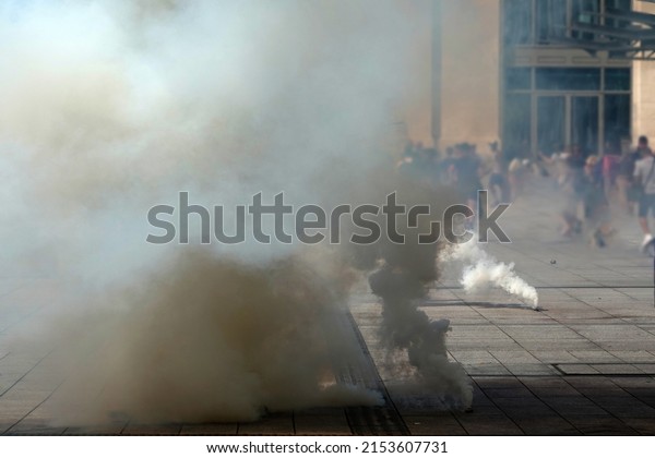 Tear gas bomb attacks on protesters. Tear gas\
bombs are smoking on the\
asphalt..