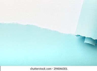 Tear in a piece of blue paper revealing white background underneath