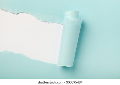 Tear in a piece of blue paper revealing white background underneath 