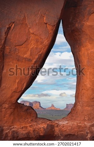 Teardrop arch frames a view of Monument Valley on the Utah-Arizona border.
