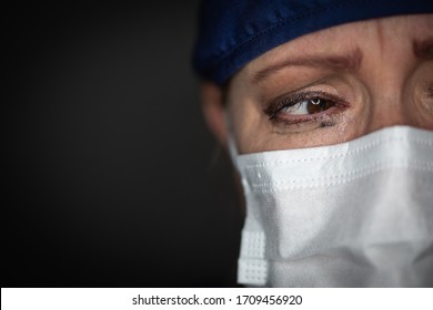 Médica o enfermera cansada usando una máscara médica de fondo oscuro.