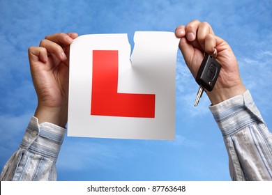 Tearing L plate against a sky holding a car key after passing driving test