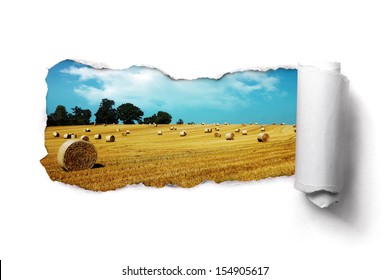 Tearing a paper frame hole to reveal hay bale field landscape